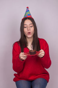 Portrait of woman holding red while standing against white background