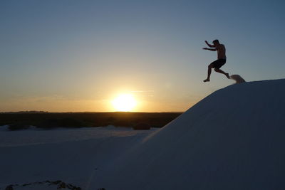 Silhouette man jumping against sky during sunset