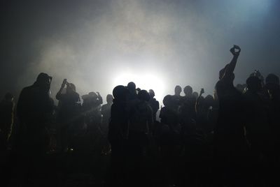 Silhouette crowd at music concert against sky at night