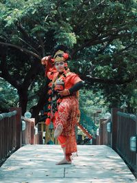 Woman standing by tree trunk