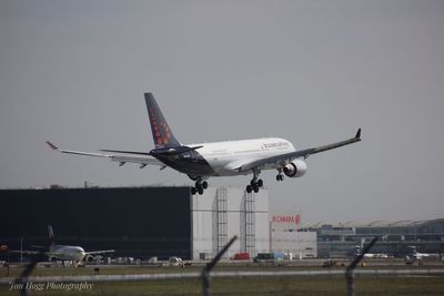 Airplane flying over airport runway against clear sky