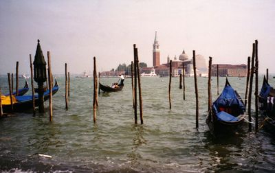 Boats moored in sea by wooden posts