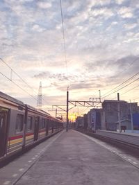 Train at railroad station against sky during sunset