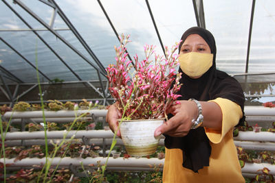 Portrait of young woman blowing bubbles in greenhouse