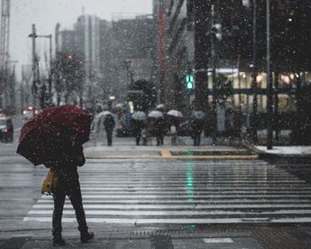 Person with umbrella crossing street during rainy season