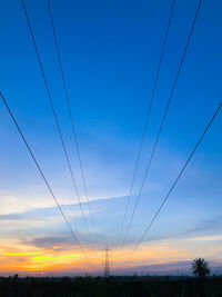 Low angle view of electricity pylon against sky during sunset