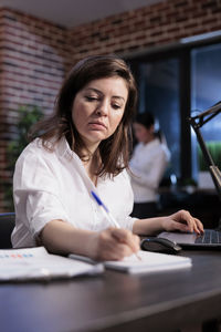 Portrait of young woman using laptop at office