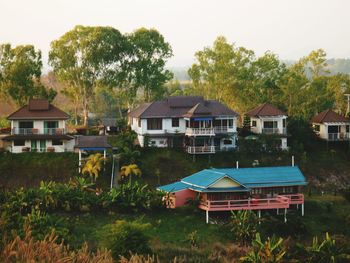 Houses and trees on field against sky