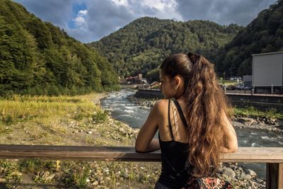 Rear view of woman leaning on railing