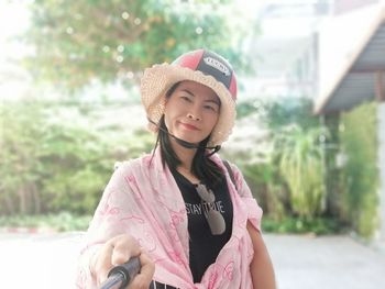 Portrait of woman holding monopod while standing at park