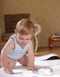 Cute baby boy painting on paper at home