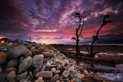 Rocks on shore against sky during sunset