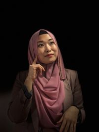 Thoughtful woman wearing hijab against black background