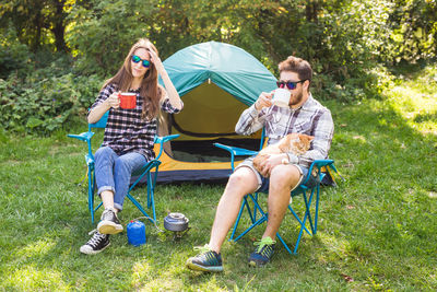 Full length of young couple sitting on grass