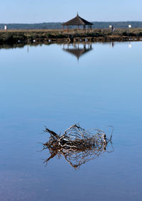 Traditional windmill by lake against sky