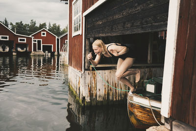 Full length of happy woman diving in lake against chalets