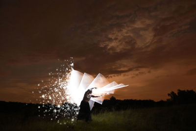 Low angle view of man standing on field against sky at sunset