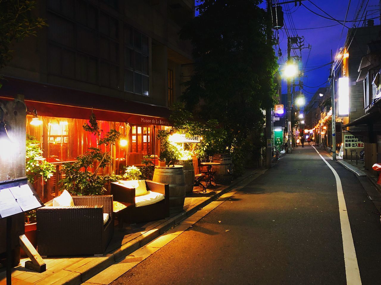 STREET AMIDST ILLUMINATED BUILDINGS AT NIGHT