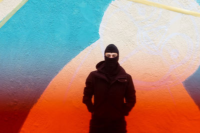 Portrait of young man standing against wall