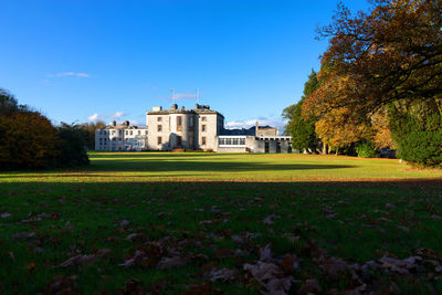 Lawn by building against blue sky