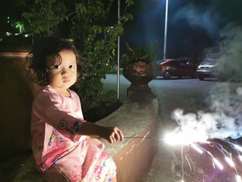 Cute girl looking at illuminated camera at night