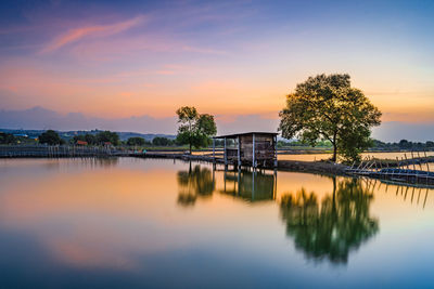 Scenic view of lake by trees against sky during sunset