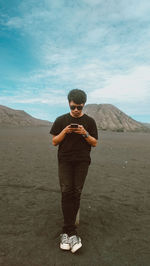 Full length of man using phone while standing on field