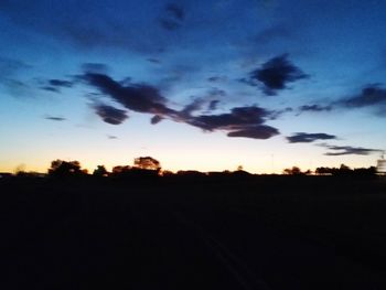 Scenic view of silhouette field against sky at sunset