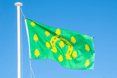 Low angle view of flag against clear blue sky