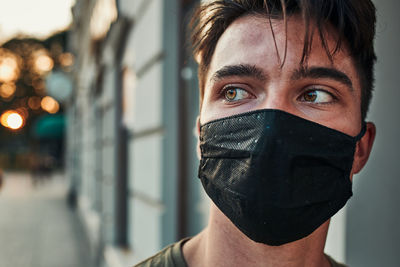 Young man wearing mask looking away outdoors