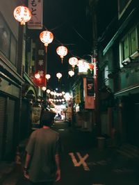 Rear view of illuminated lanterns hanging on street in city at night