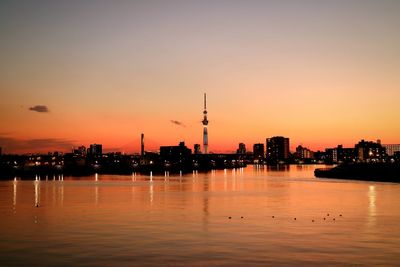 Silhouette of city at waterfront during sunset