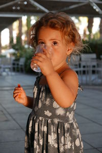 Close-up of cute girl looking up while drinking water