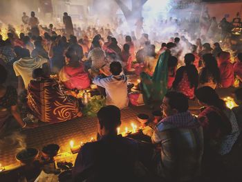 Rear view of people praying while sitting on land