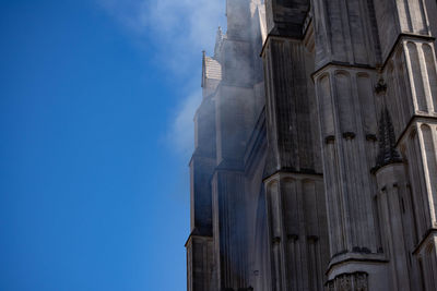 Low angle view of smoke emitting from building against sky