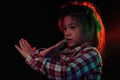 Portrait of girl looking away against black background