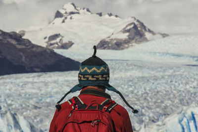 Rear view of man standing on snowcapped mountain