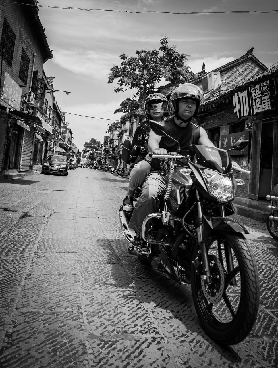 transportation, building exterior, mode of transportation, architecture, one person, real people, portrait, city, street, built structure, motorcycle, lifestyles, looking at camera, ride, land vehicle, riding, sky, leisure activity, full length, outdoors