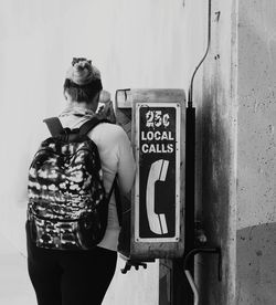 Young woman standing by text on wall