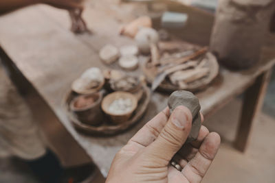 Man molding clay to make ceramics with his hands, artisan working in his workshop, selective focus