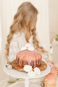 A girl with long hair in a light dress is sitting at the easter table. happy easter celebration.