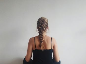 Woman with braided hair standing against wall