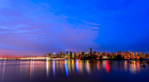 Illuminated buildings in city against blue sky