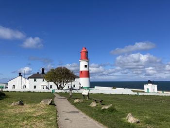 Lighthouse by sea against sky