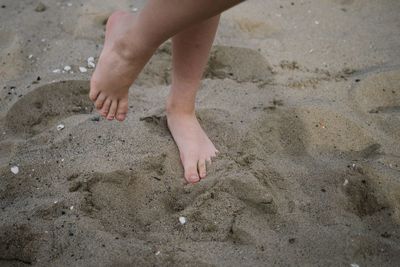 Low section of child walking on sand at beach