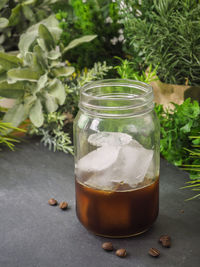 Iced coffee in mason jar with beans on table
