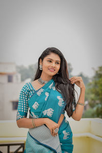 Portrait of young woman standing against wall