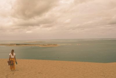 Woman standing on beach against sky