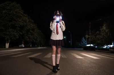 Rear view of woman standing on road at night