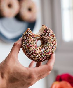 Cropped hand holding donut on table